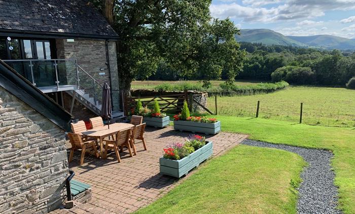 The Longhouse at Hilltops Brecon Holiday Cottages has a private outdoor patio area with views across open fields to the Camarthen Fans